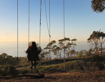 woman sits on secret swing in La Jolla overlooking Pacific Ocean