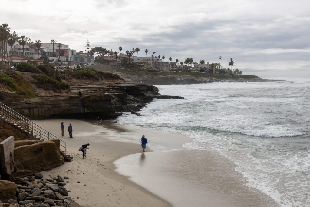 a handful of beachgoers enjoy the small south casa beach in La Jolla on a cloudy day