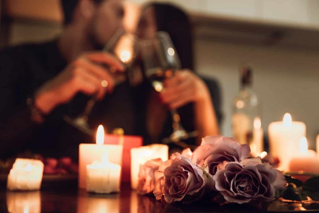 couple shares romantic moment at dinner with candles and champagne