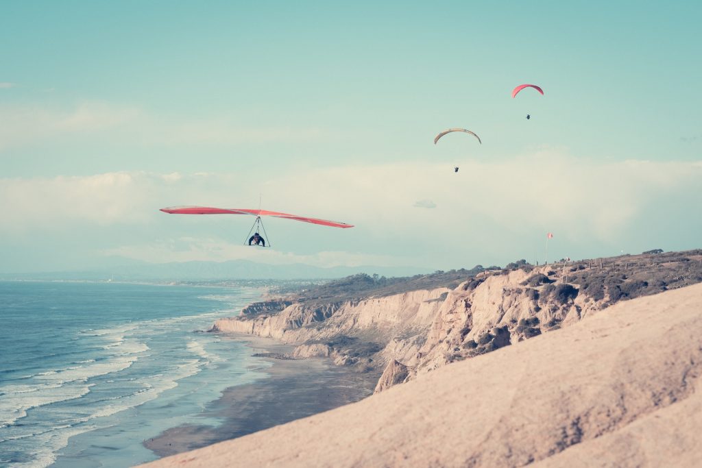 three paragliders fly over the cliffs of Torrey pines in La Jolla 