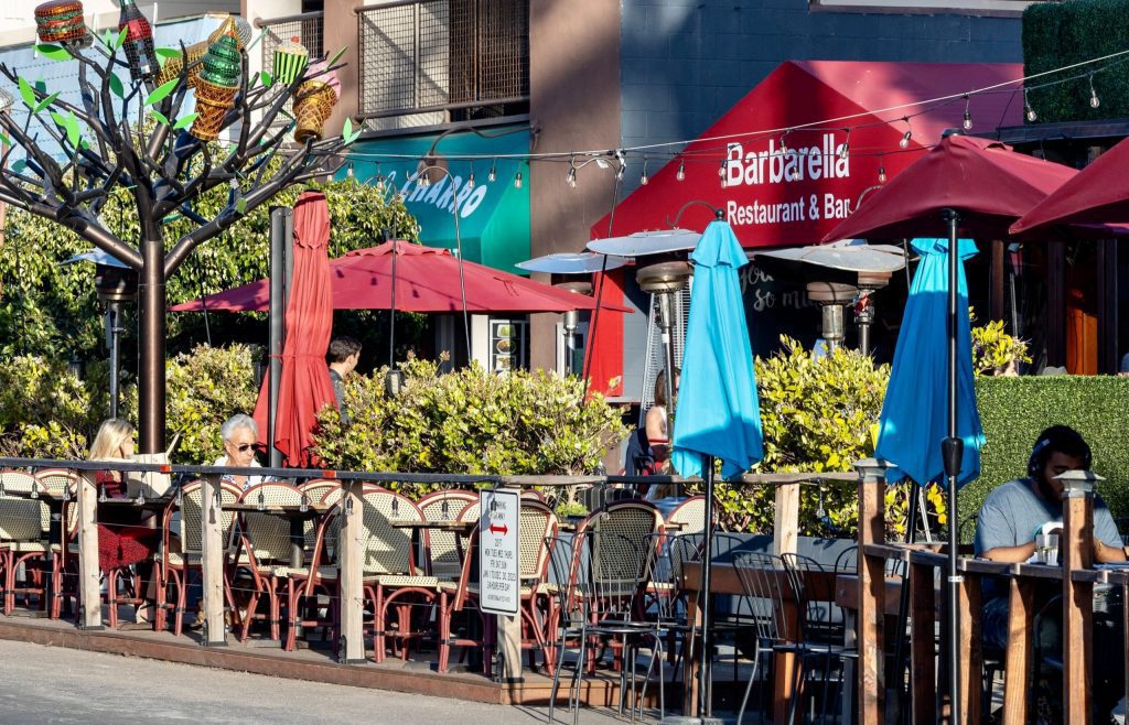 streetside dining in La Jolla shores in front of Barbarella restaurant table and chairs and umbrellas