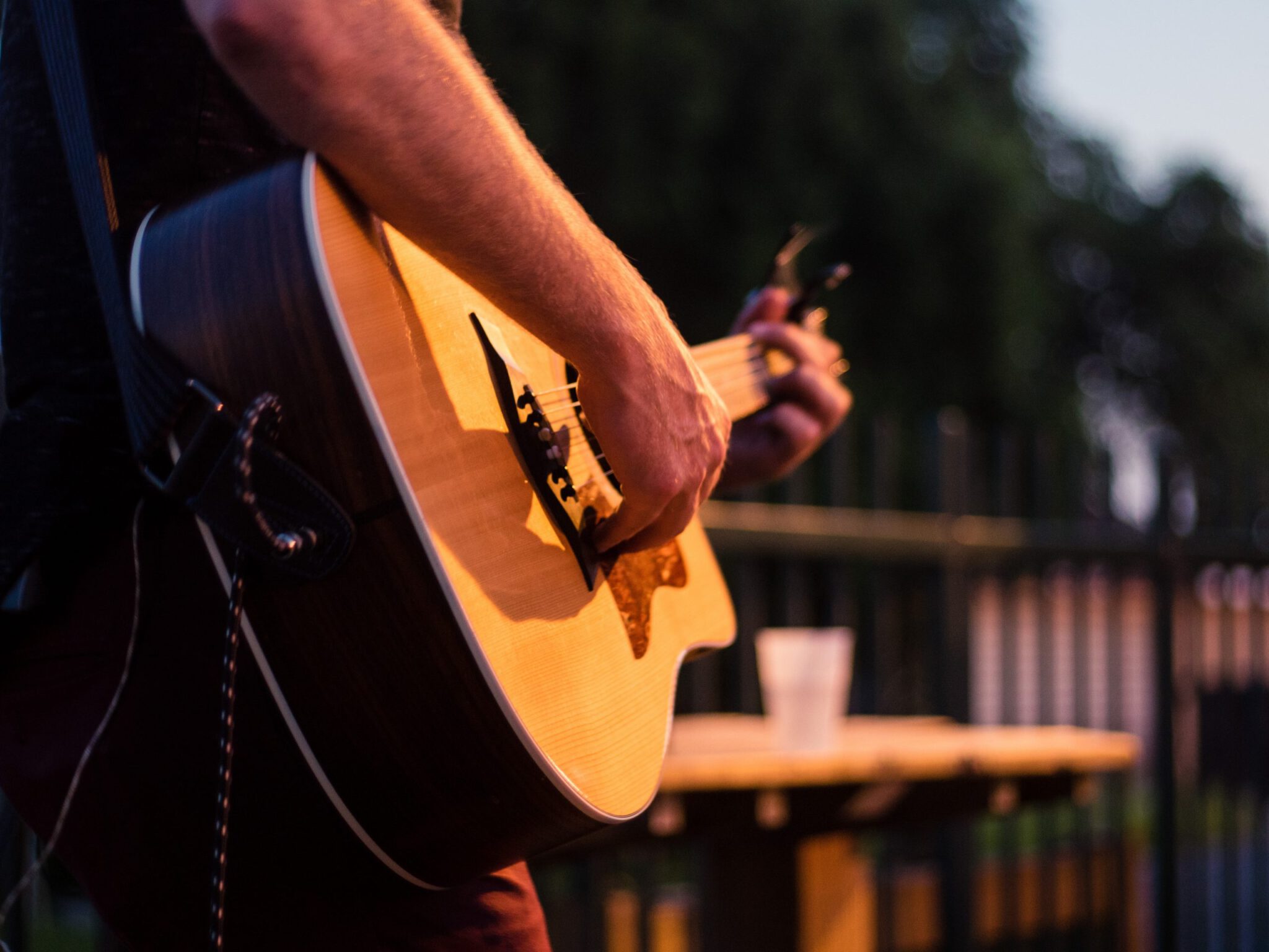 man strums acoustic guitar on outdoor patio