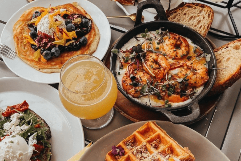 A dining table shows a small skillet with shrimp, a waffle, and mimosa at one of the top cafes in La Jolla