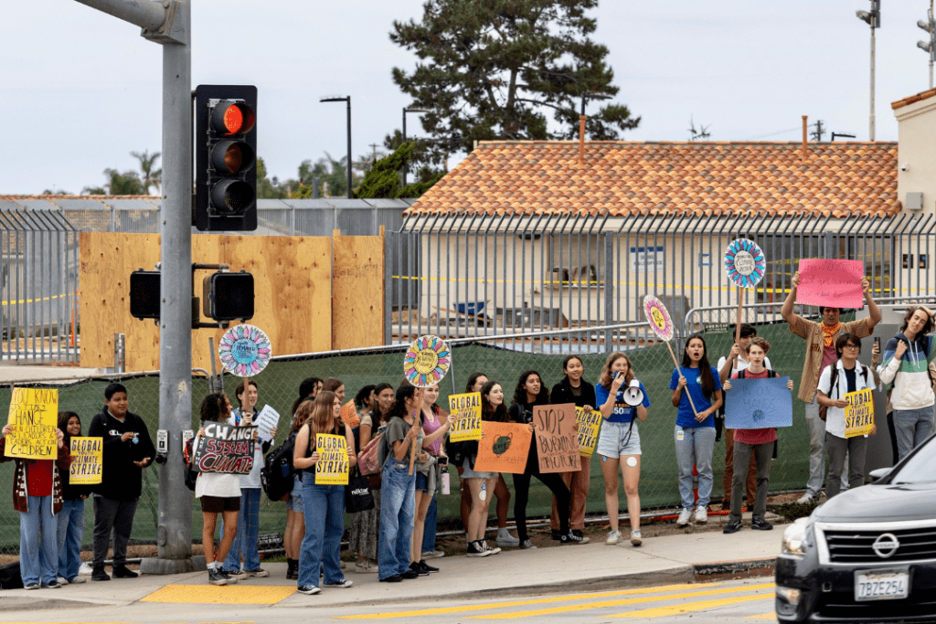 students strike on the street outside of La Jolla high school, walk out of class for climate action holding signs