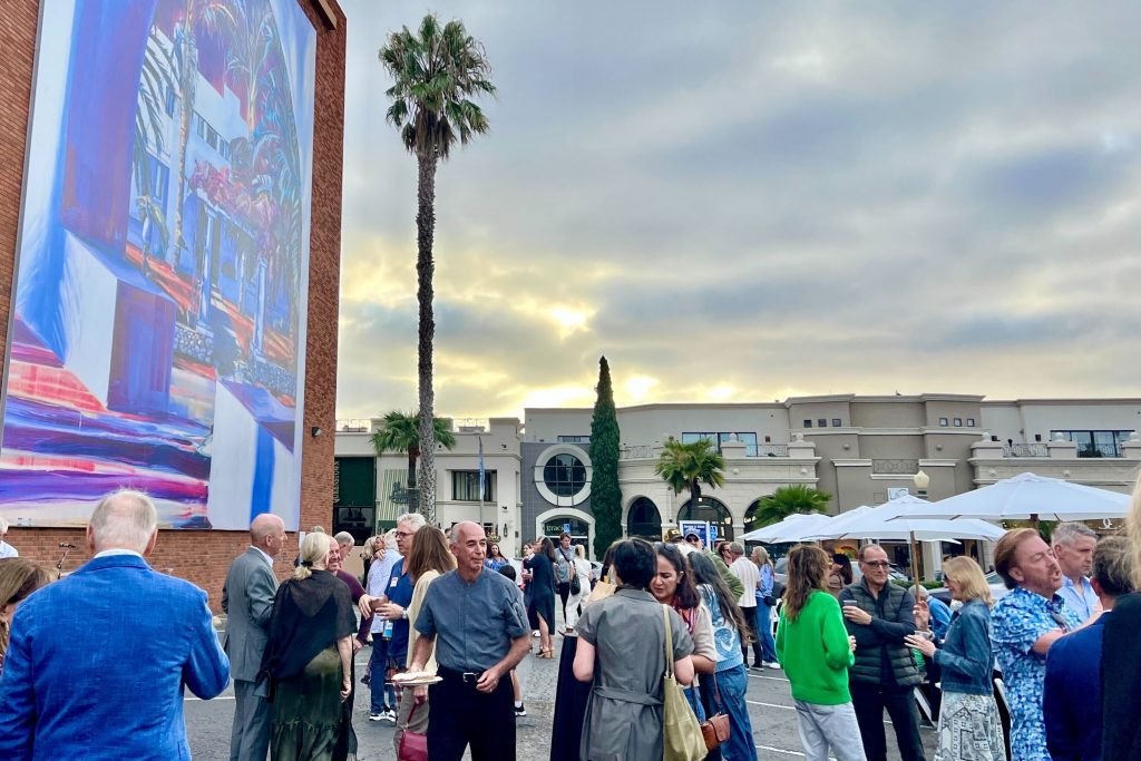 party goers at the murals of La Jolla enrichment party gather under one of la jollas street murals