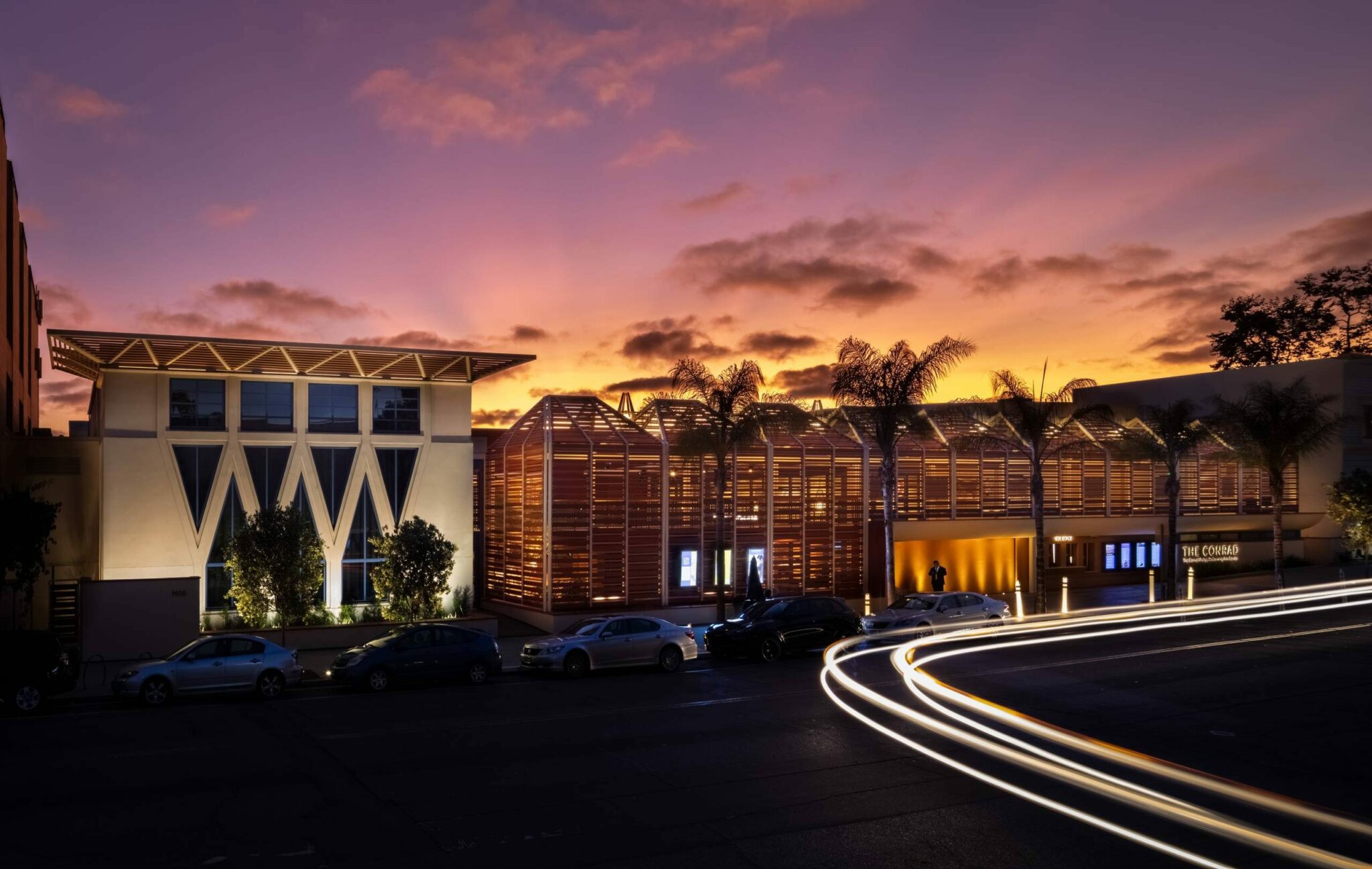 The Conrad performing arts center building at sunset,yellow pink and purple sky with clouds and palm trees. event site for the blue water film festival.
