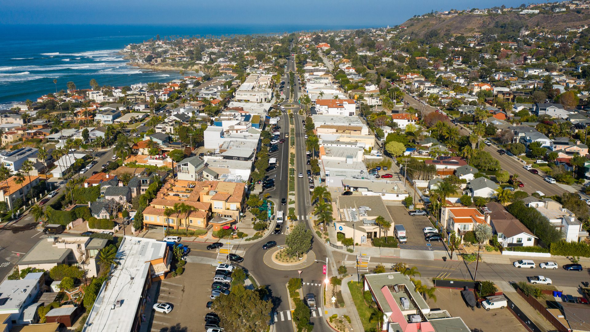 drone view of the community of bird rock with merchants on either side of street. Pacific Ocean on horizon