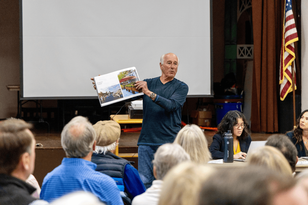 male resident holds up booklet demonstrating arguments in favor of the parking plan in La Jolla shores