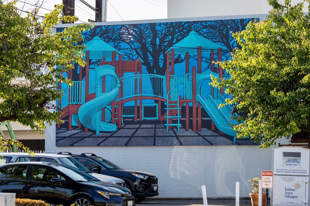 new mural installed in La Jolla by Amy Adler depicts a life size painting of a childrens playground installed on side of building