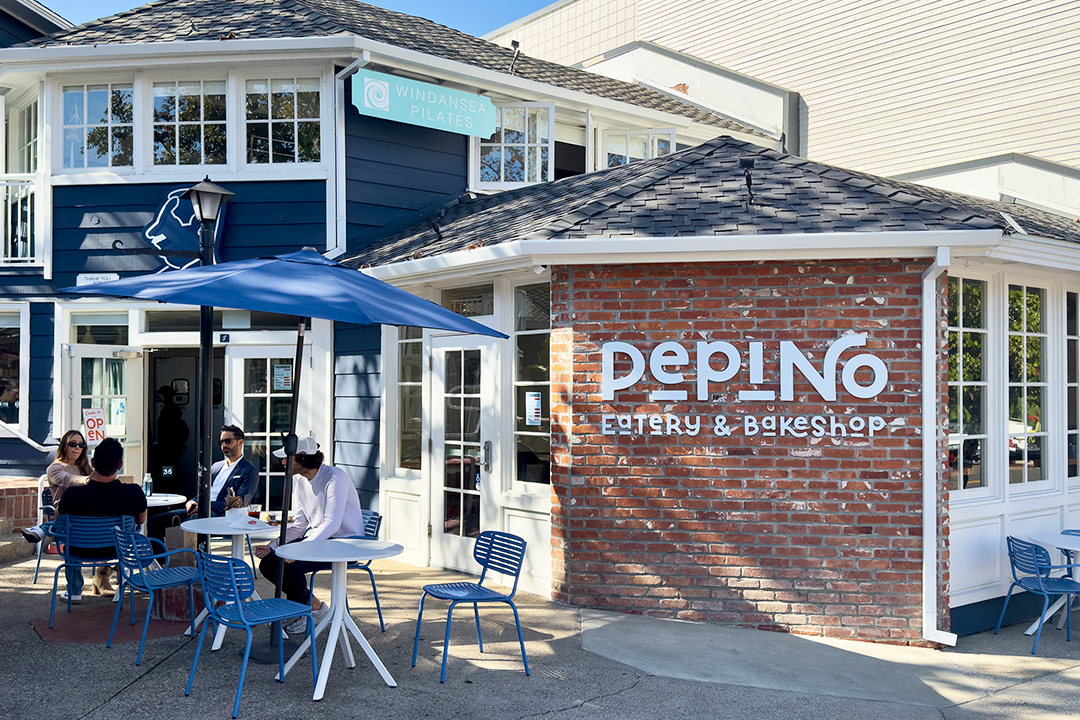 Pepino La Jolla eatery and bakeshop exterior featuring blue and white coastal architecture, brick signage, outdoor patio with blue umbrellas and chairs on Fay Avenue in La Jolla
