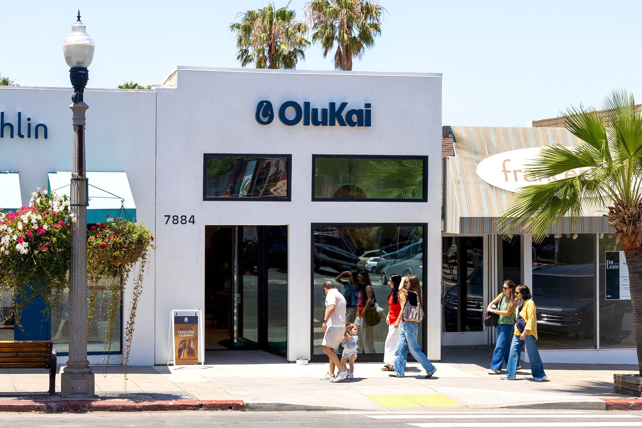 OluKai La Jolla storefront at 7884 Girard Ave in The Village, with pedestrians walking past on a sunny day.