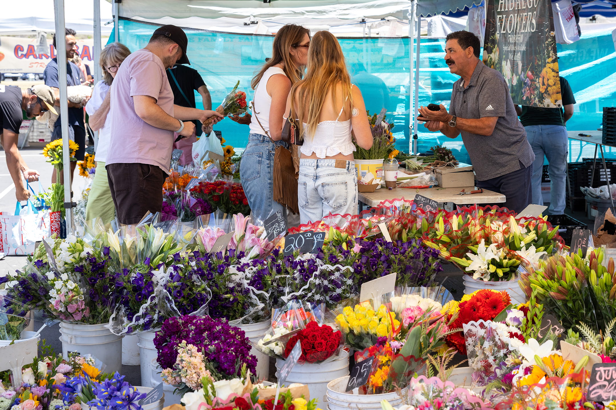 Shoppers browse colorful bouquets of lilies, roses, and wildflowers at the Hidalgo Flowers stand at the La Jolla Open Aire Market.