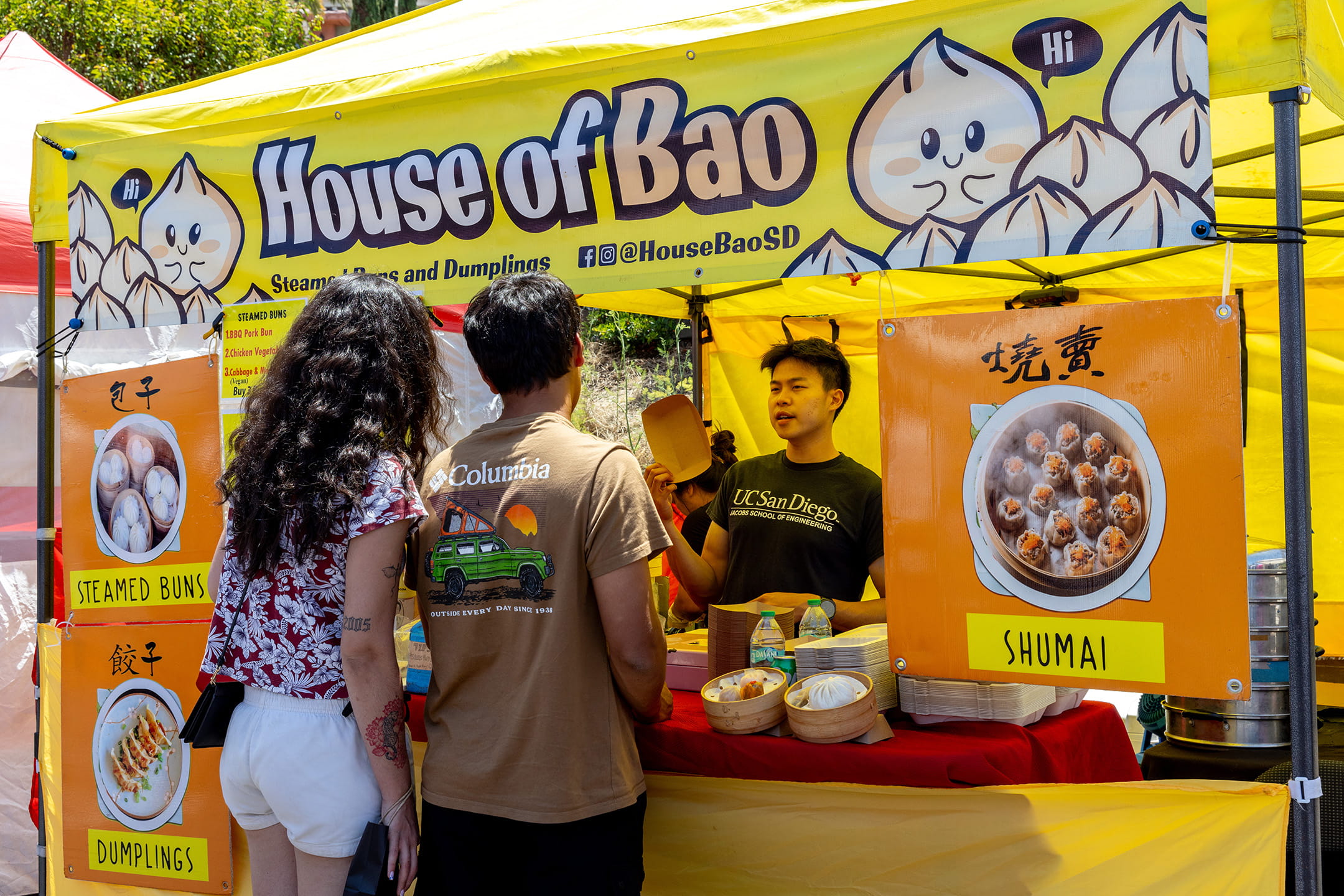Customers order steamed buns, dumplings, and shumai from the House of Bao vendor booth at the La Jolla Open Aire Market.