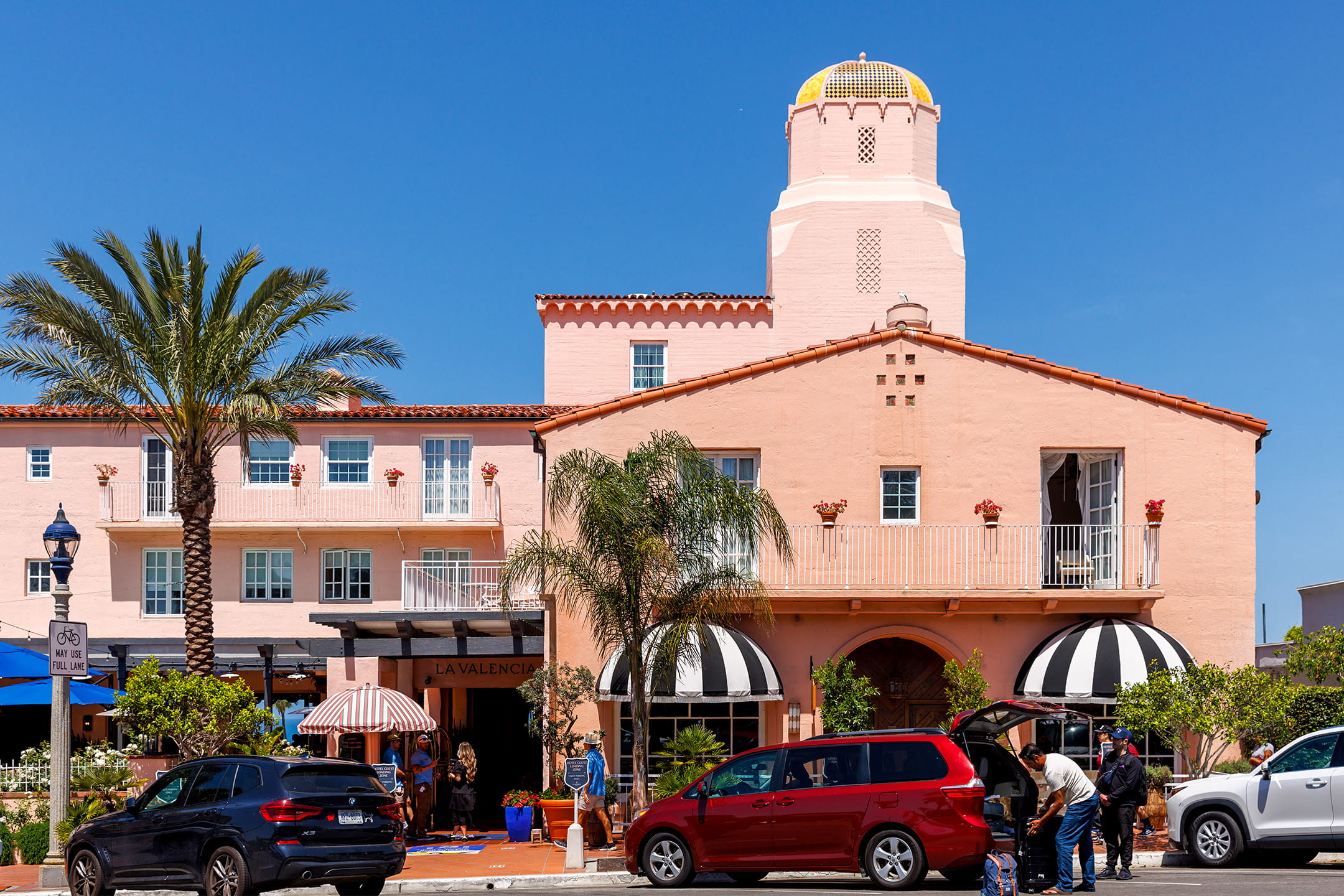 La Valencia, a pink Spanish Colonial La Jolla luxury hotesl with its iconic tiled tower, palm trees and striped awnings along the entrance.