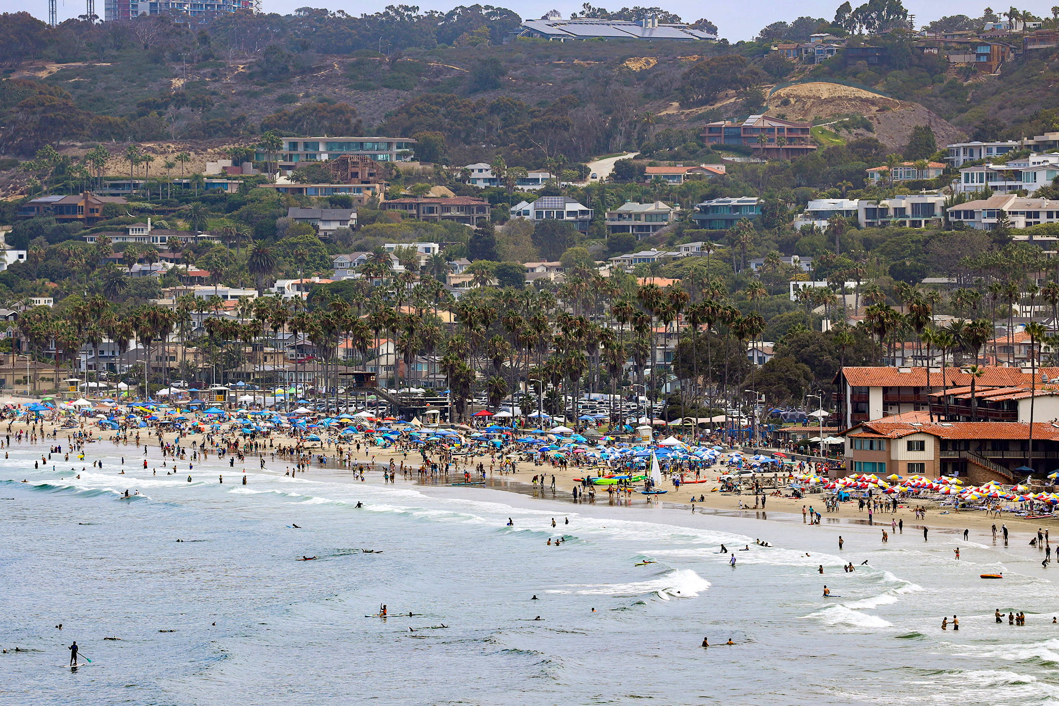 Crowded La Jolla Shores beach with surfers and umbrellas, a popular labor day weekend in San Diego destination